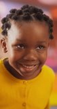 Vertical Screen: Close Up Portrait of an Adorable Little Black Girl with Brown Eyes Looking at Camera, Smiling Happily. Smart Talented Girl Laughing and Having Fun in Daycare