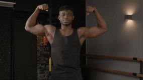 Positive handsome sporty muscular build African man posing in front double biceps pose, looking with cheerful smile, showing strength, confidence and masculinity in health club. - Powered by Shutterstock - Get 15% off with code: PIKWIZARD15