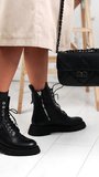 Lady in coat demonstrates black leather boots and bag. Model presenting fashionable stylish clothes and footwear. Vertical video.