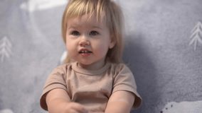 Cute kid toddler looks at the TV and smiles, focused gaze behind the camera. 4k video.