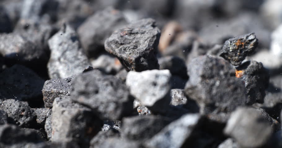 Super slow motion macro of falling gravel stones on ground during quality control and sorting process at concrete plant industrial factory at 1000 fps.