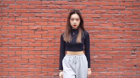 young asian woman dancing against gray wall, young people street dance youth culture, 4k slow motion clip