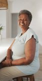 Vertical video of portrait of happy senior african american woman alone at home. senior healthcare and medical physiotherapy treatment.