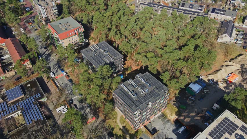 Cinematic aerial of modern apartment buildings with photovoltaic solar panels on rooftop