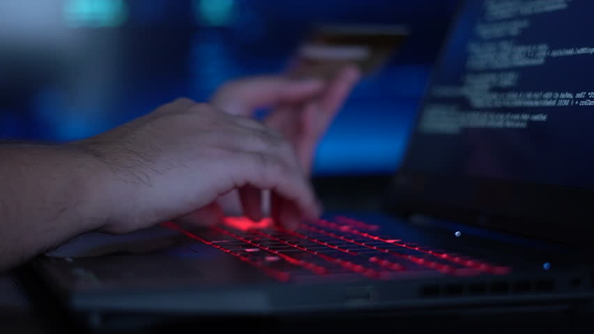 A cybercriminal sitting in front of a laptop steals an account from a bank card Royalty-Free Stock Footage #3455384327