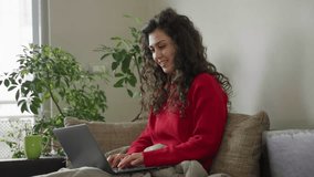 curly hair girl with red sweater sitting on a sofa and having a business meeting and discussing plans about work 