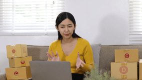 Young woman at home is doing extra work at home by selling clothes online. She is live-streaming her online sales on social media.