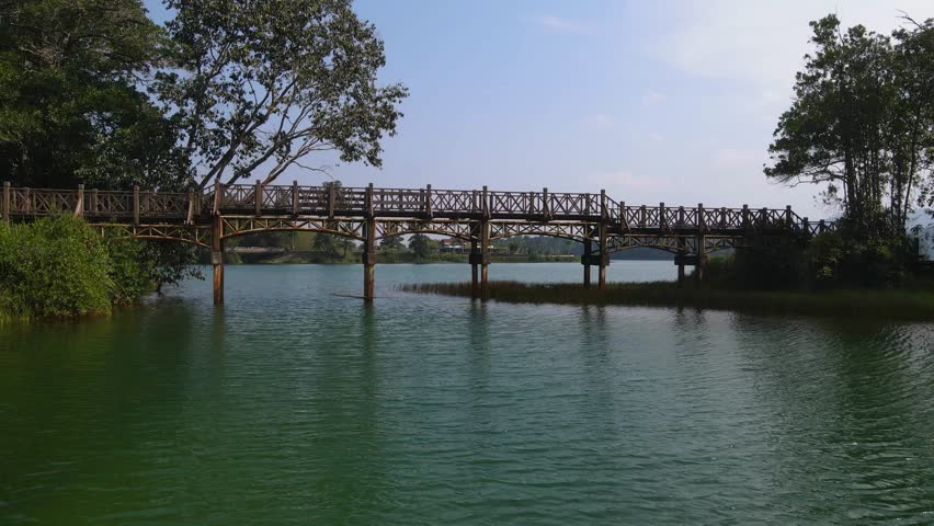 large wooden bridge over the river with a place for boats to sail under it. The banks of the river are lined with stone