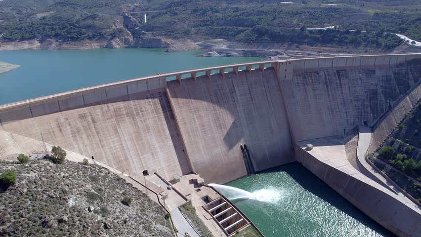 Dam and water reservoir. Panoramic aerial view of the dam and hydroelectric plant rising. Ascending aerial orbit. Renewable energies.