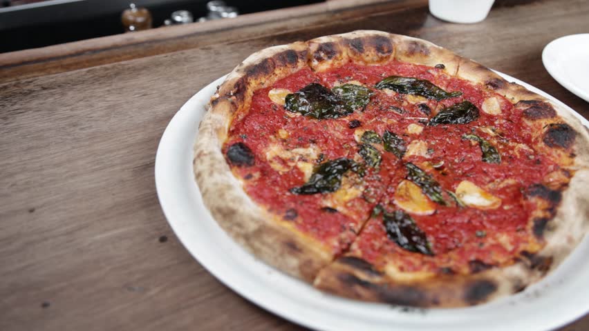 Cooked marinara pizza on a plate inside Pizzeria Bianco in Phoenix, Arizona with video panning moving in a circle.