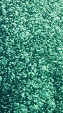 Vertical video, Camera accompanies a lot of air bubbles rising from depths of sea up to surface of blue water, slow motion. Motion of air bubbles rise up in blue water on bright sunny day in sunlight