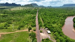 Soar above the Pantanal on a captivating drone journey. Witness scenic roadways winding through lush greenery, all set against a backdrop of majestic green mountains. 