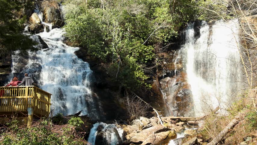 tilt footage of the rushing water, rocks and waterfall at Anna Ruby Falls with lush green trees and plants in Helen Georgia USA