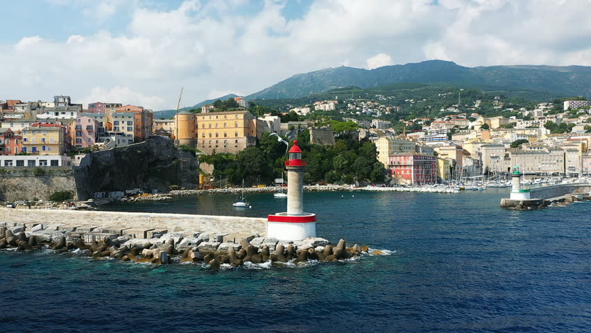 The lighthouse of the city of Bastia and its port at the foot of the mountains, in Europe, in France, in Corsica, by the Mediterranean Sea, in summer, on a sunny day.