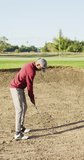 Vertical video of african american male golf player playing at golf course on sunny day. healthy and active time.