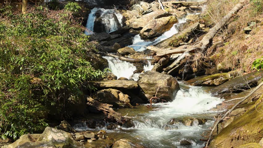 footage of the rushing water, rocks and waterfall at Anna Ruby Falls with lush green trees and plants in Helen Georgia USA