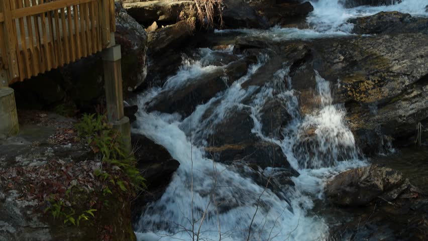 slow motion footage of the rushing waters of Smith Creek and waterfall at Anna Ruby Falls with rocks and lush green trees and plants in Helen Georgia USA