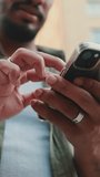 VERTICAL VIDEO: Close-up of the hands of young man using cellphone