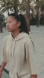 VERTICAL VIDEO, girl wears sportswear, climbs the stairs at morning time on the embankment background