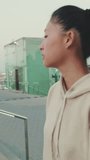 VERTICAL VIDEO, girl wears sportswear, climbs stairs, looks up at morning time