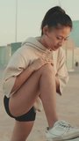 VERTICAL VIDEO, girl in sportswear doing workout, stretching at morning time on modern buildings background