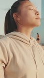 VERTICAL VIDEO, girl in sportswear doing workout, breathing exercises, relaxing at morning time
