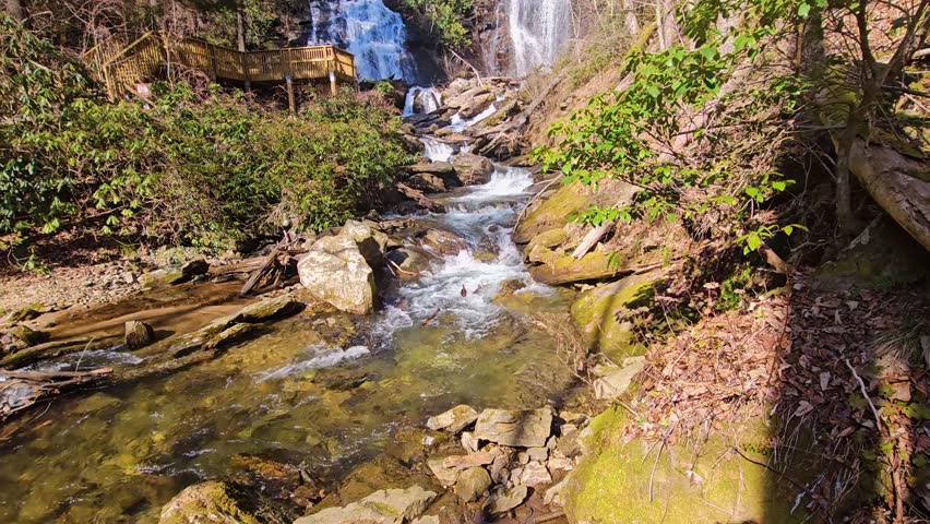 tilt footage of the rushing waters of Smith Creek and waterfall at Anna Ruby Falls with rocks and lush green trees and plants in Helen Georgia USA