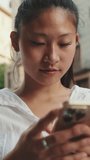 VERTICAL VIDEO: Close up, young woman using mobile phone while standing next to the road