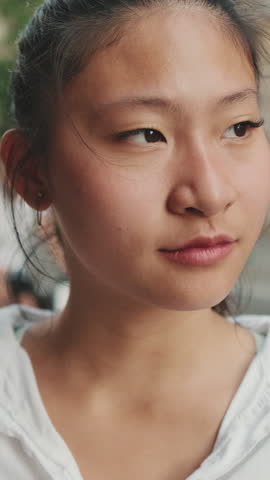 VERTICAL VIDEO: Close-up of young woman looking at the camera and smiling