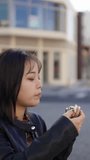 A vertical video of a young Japanese Okinawan woman in her 20s eating fast food pork egg rice balls on Kokusai Street, a tourist attraction in Naha City, Okinawa Prefecture