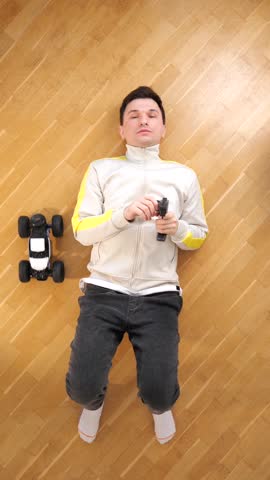 vertical video man lying on his back controls toy rc car with a remote control