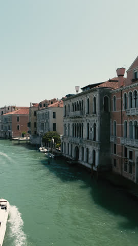 Vertical video, Canal in Venice, Boats and gondolas with tourists float along canal, on sunny day, Camera moves sideway to left side