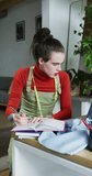 Vertical video of caucasian non-binary transgender woman working at home, taking notes. spending quality time at home alone, body inclusivity.