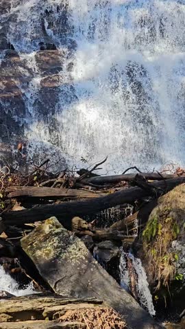 tilt footage of the rushing waters of Smith Creek and waterfall at Anna Ruby Falls with rocks and lush green trees and plants in Helen Georgia USA