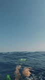 POV shot, man paddling with his fins underwater sailing in open sea. First person video, guy swims on surface in water of Mediterranean sea. Vertical video, Close-up