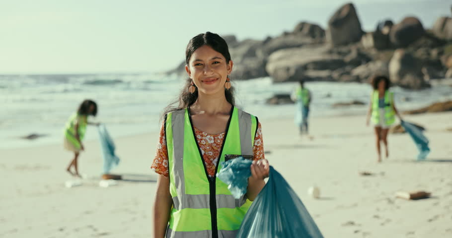 Portrait, beach and woman with a trash bag, recycle and smile with plastic collection and environment. Face, people or group with girl or volunteer with sustainability and ecology with climate change