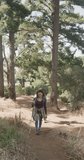 Vertical video of biracial couple hiking with trekking poles in forest, slow motion. Spending quality time, lifestyle, nature, hiking and camping concept.