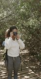 Vertical video of biracial couple taking pictures in forest, slow motion. Spending quality time, lifestyle, nature, hiking and camping concept.