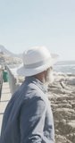 Vertical video of senior african american man on promenade by the sea, slow motion. Spending quality time, lifestyle, vacation and retirement concept.