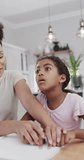 Vertical video of biracial mother and daughter reading braille, slow motion. Spending quality time at home, domestic life, family, disability and blindess.