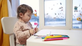 baby girl draws while sitting at a table by the window at home. happy family kid concept. baby daughter learns to draw with pencils on sheet of paper indoors. development of fine motor skills dream - Powered by Shutterstock - Get 15% off with code: PIKWIZARD15