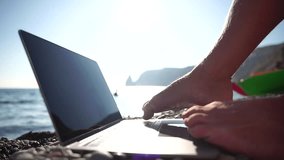 Man laptop sea. Working remotely on seashore. Happy successful man, male freelancer working on laptop by foot, relieves stress from work to restore life balance. Freelance, remote work on vacation