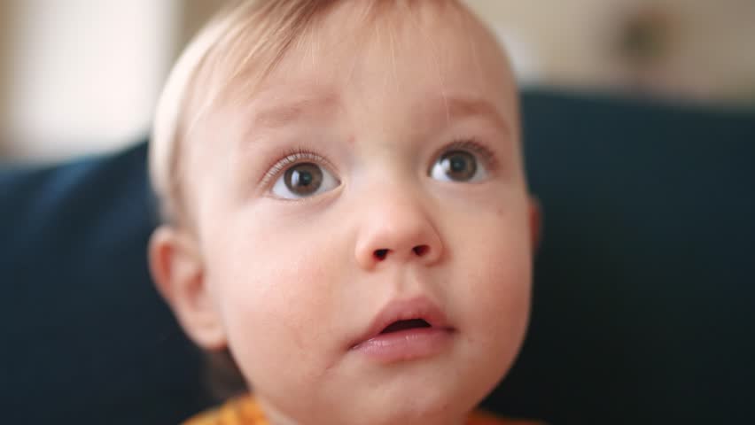 baby portrait close-up looking at camera. happy family kid dream concept. baby blond indoors at home looking at the camera. child son lifestyle smiling sitting on the sofa close-up