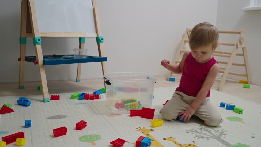 The child himself cleans up toys in the nursery after the game. Toddler baby collects toys in a box. Kid girl aged 2,5 year old. Royalty-Free Stock Footage #3455924285