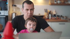 father working from home remotely with baby daughter in his fun arms. pandemic remote work business concept. father tries to work at home in kitchen, baby children interfere sitting on their hands - Powered by Shutterstock - Get 15% off with code: PIKWIZARD15