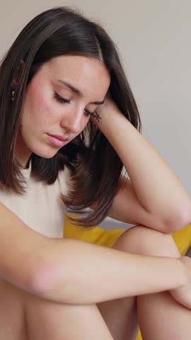Portrait of upset young adult woman feeling sad sitting on bed feeling sad at home
