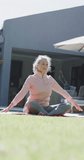 Vertical video of happy senior caucasian woman doing yoga, stretching in garden, slow motion. Spending quality time, retirement, sport and healthcare.