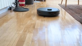 A slow-motion of an autonomous robot vacuum cleaner is seen mopping at high-speend a hardwood floor in a home living room.