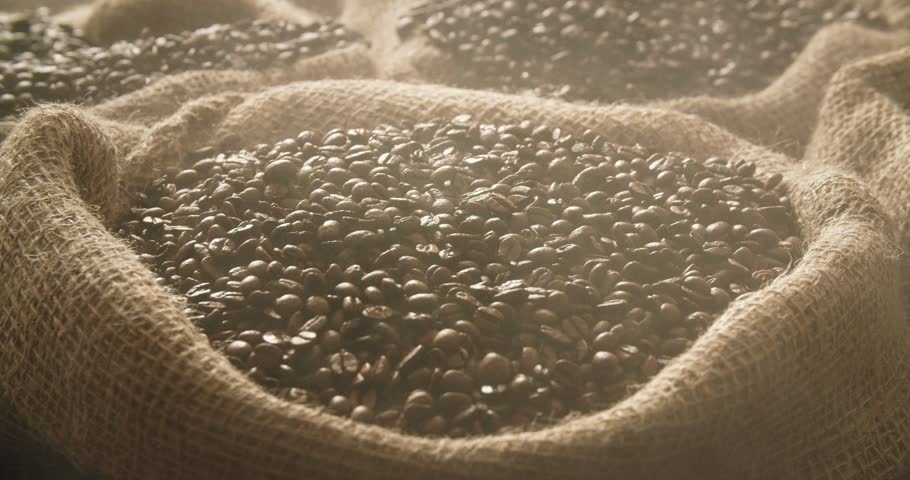 Fresh roasted coffee beans falling into linen sack in slow motion. Medium close up of coffee beans dropped into linen bag. Royalty-Free Stock Footage #3456085757