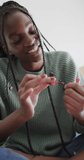 Vertical video of happy african american teenage girl painting nails in slow motion. Domestic life, makeup and joy.